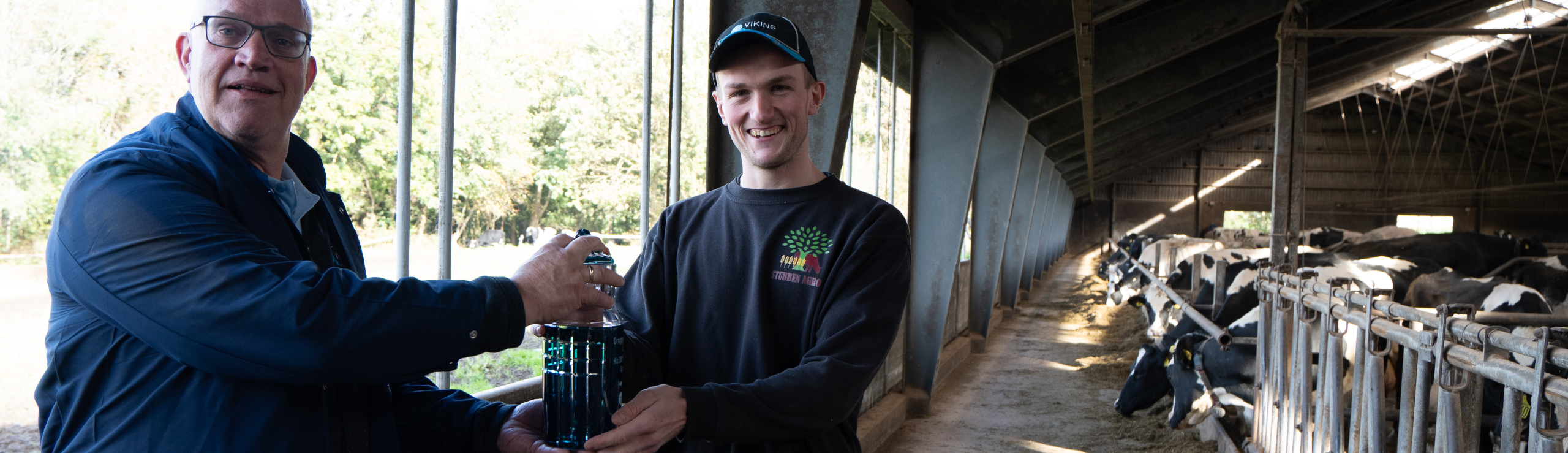 Ydelsestekniker Harmen Scholten Overrækker Gave Fra IDEXX – En Unikt Fremstillet Mælkejunge I Glas